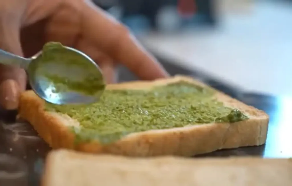 applying green sauce on bread slice