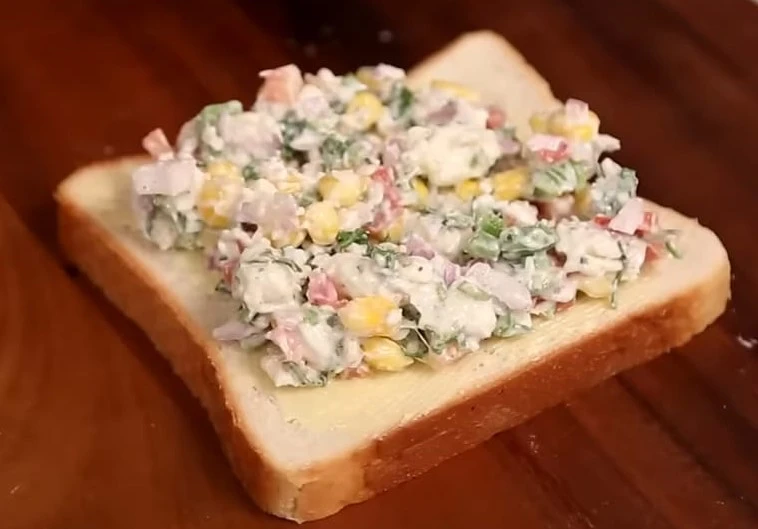 spreading filling on corn capsicum sandwich