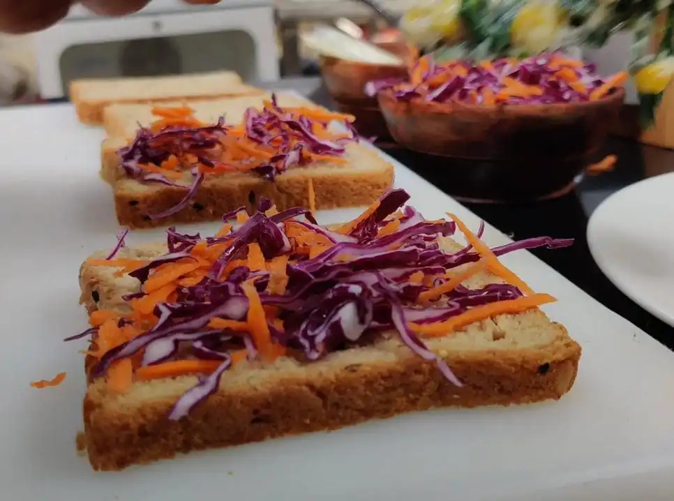 spreading grated carrot on bread slice