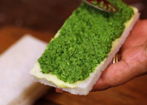 spreading green chutney over bread slice