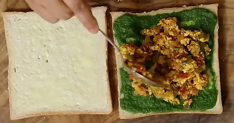 spreading paneer bhurji on sandwich