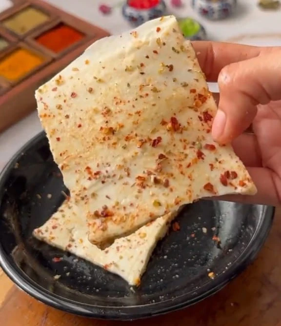 spices are sprinkled over paneer slice